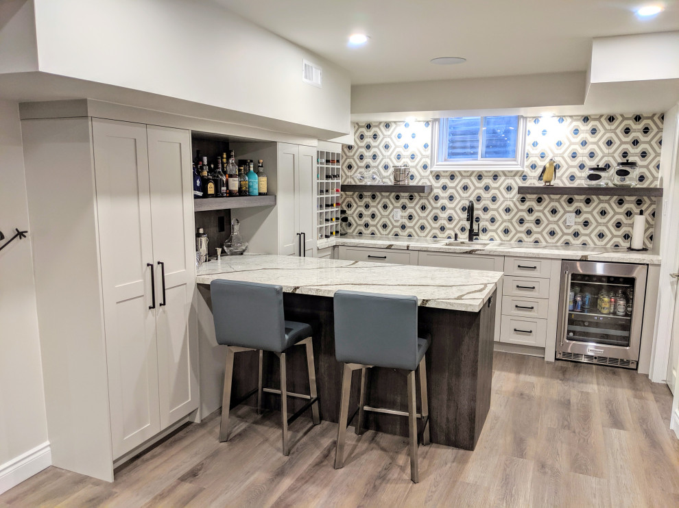 Inspiration for a mid-sized transitional l-shaped wet bar in Toronto with an undermount sink, shaker cabinets, grey cabinets, quartz benchtops, multi-coloured splashback, cement tile splashback, vinyl floors, brown floor and white benchtop.