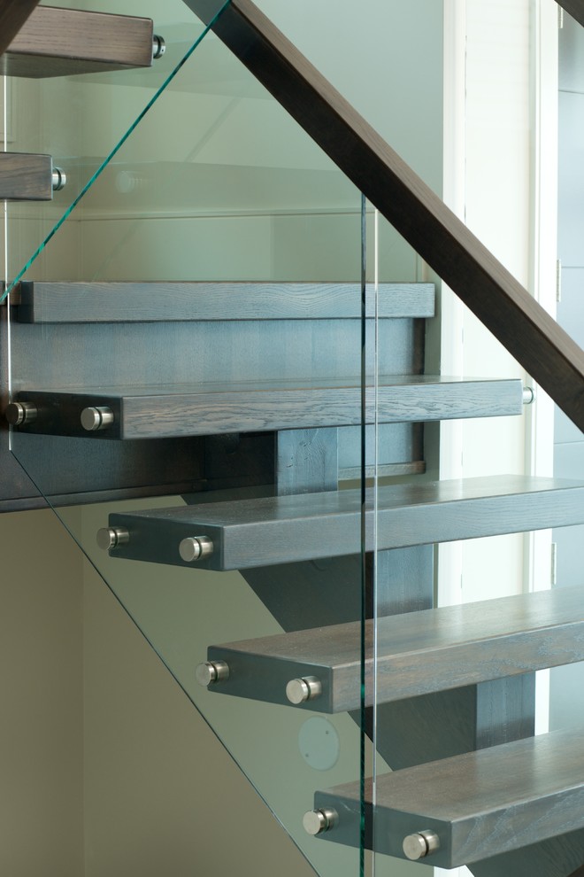 Design ideas for a modern wood straight staircase in Edmonton with open risers and glass railing.