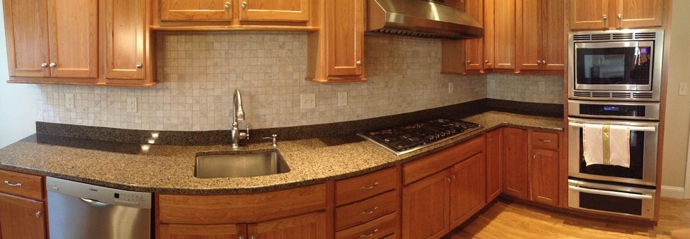 Example of a transitional l-shaped vinyl floor eat-in kitchen design in Boston with no island, an undermount sink, recessed-panel cabinets, light wood cabinets, granite countertops, beige backsplash, stone tile backsplash and stainless steel appliances