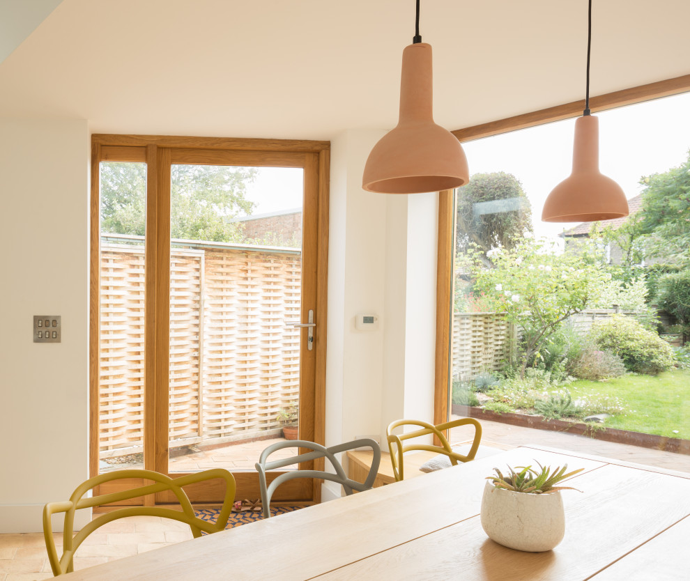 Mid-sized contemporary kitchen/dining combo in Cambridgeshire with white walls, terra-cotta floors and pink floor.
