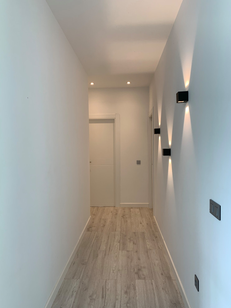 Aménagement d'un petit couloir moderne avec un mur blanc, un sol en carrelage de porcelaine et un sol marron.