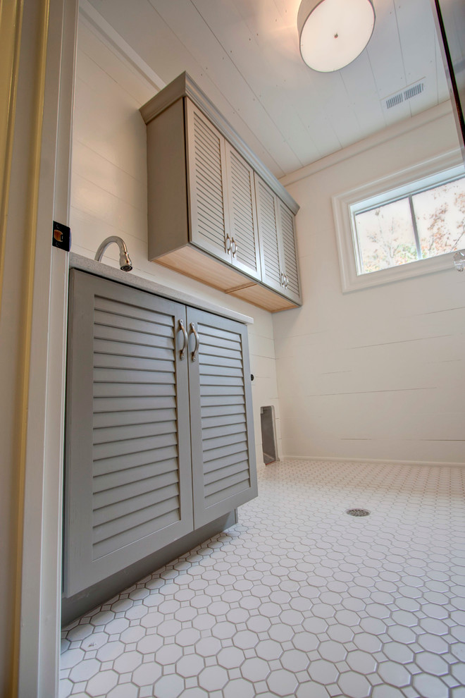 Design ideas for a mid-sized transitional single-wall dedicated laundry room in Raleigh with an undermount sink, louvered cabinets, grey cabinets, white walls, ceramic floors and a side-by-side washer and dryer.