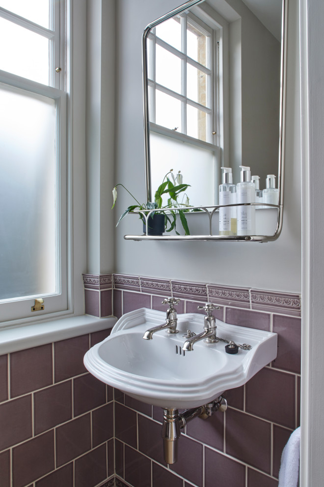 Photo of a mid-sized country powder room in London with a two-piece toilet, ceramic tile, purple walls, limestone floors, a wall-mount sink and beige floor.