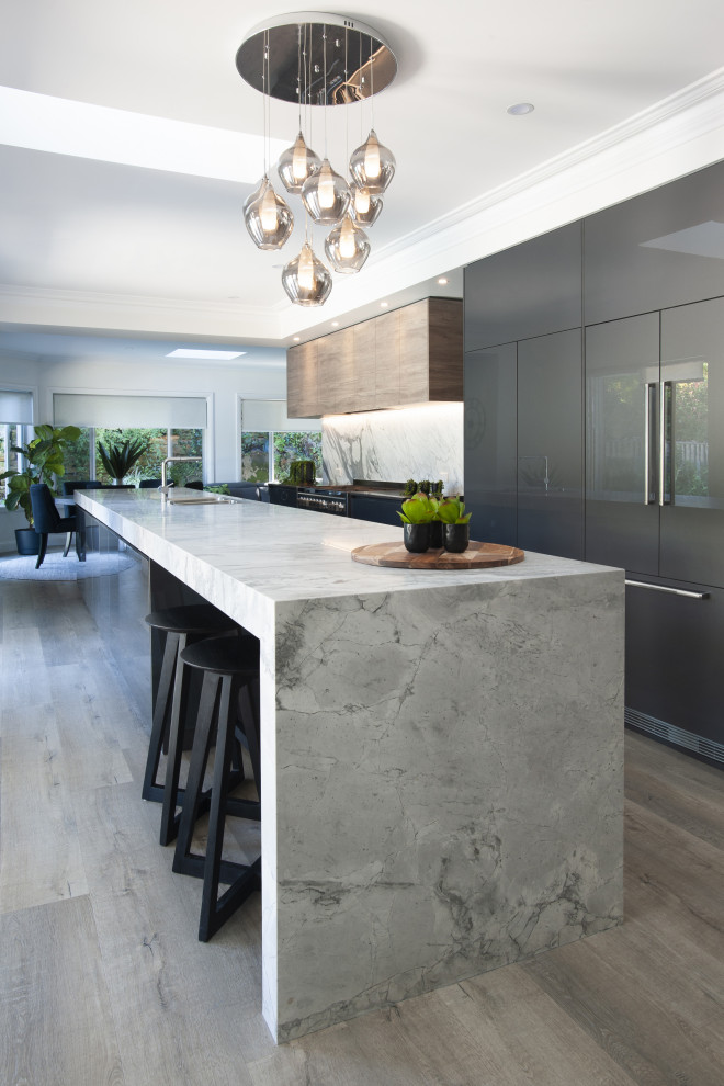 Contemporary galley kitchen in Sydney with an undermount sink, flat-panel cabinets, grey cabinets, panelled appliances, dark hardwood floors, with island, brown floor and grey benchtop.