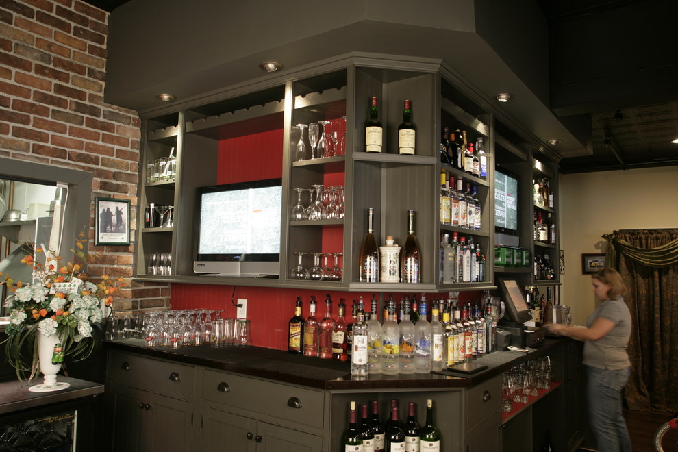 This is an example of a transitional single-wall seated home bar in New York with shaker cabinets, green cabinets, solid surface benchtops and red splashback.