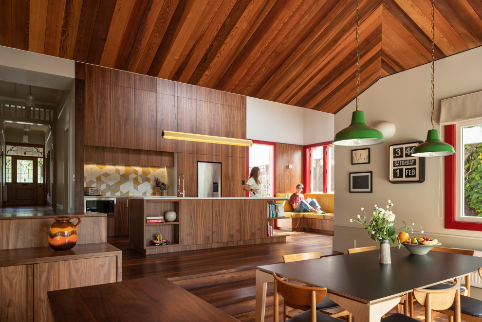 Midcentury dining room in Auckland with white walls, dark hardwood floors, brown floor, vaulted and wood.