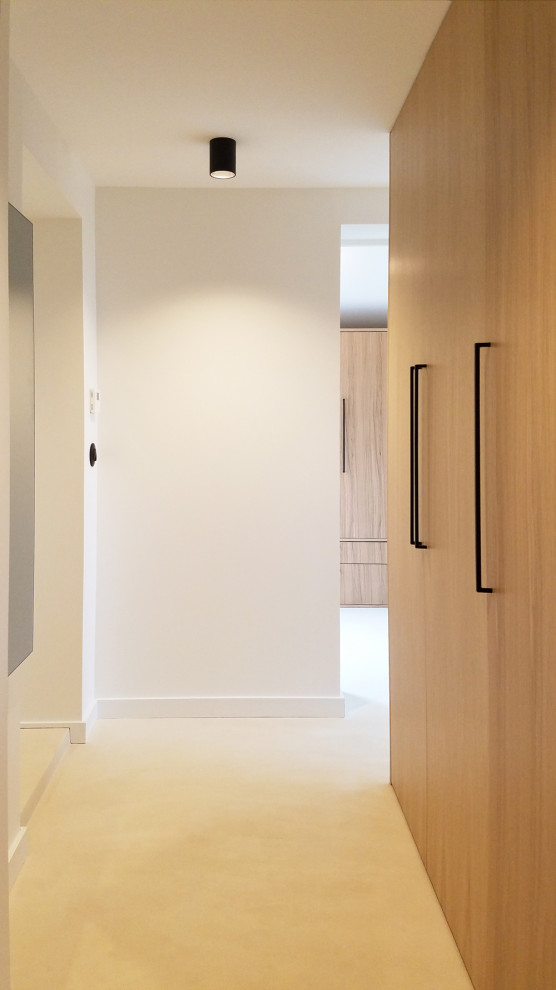 Imagen de armario y vestidor unisex contemporáneo pequeño con armarios con rebordes decorativos, puertas de armario de madera clara, suelo de cemento y suelo beige