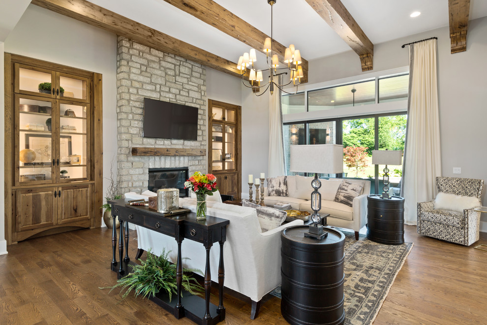 Country enclosed living room in Cincinnati with grey walls, medium hardwood floors, a standard fireplace, a stone fireplace surround, a wall-mounted tv and brown floor.