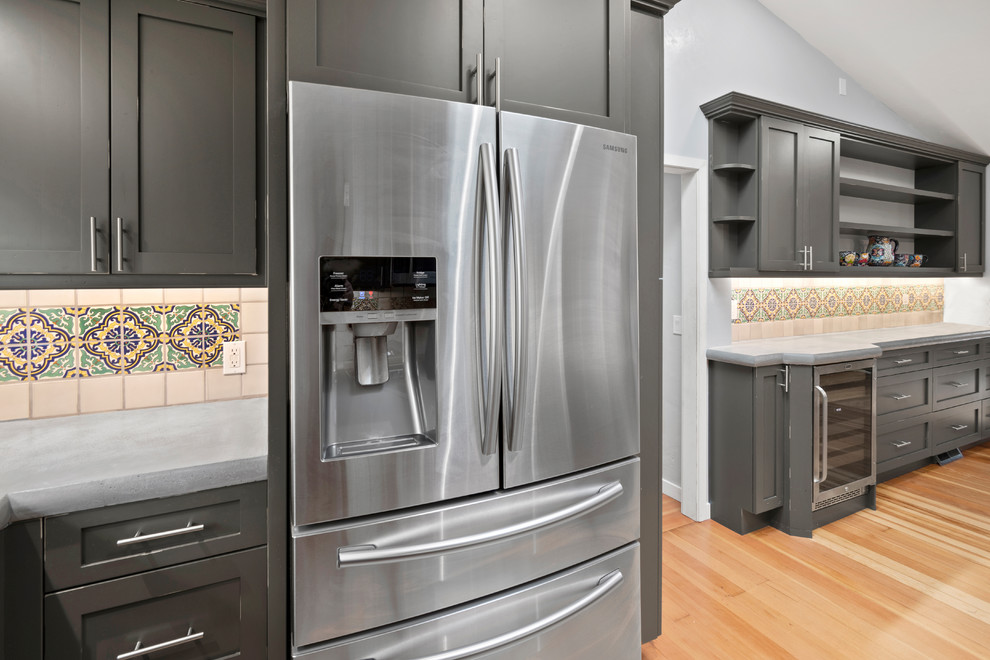This is an example of a small traditional u-shaped kitchen in San Francisco with an undermount sink, shaker cabinets, distressed cabinets, concrete benchtops, ceramic splashback, stainless steel appliances, medium hardwood floors, brown floor and grey benchtop.