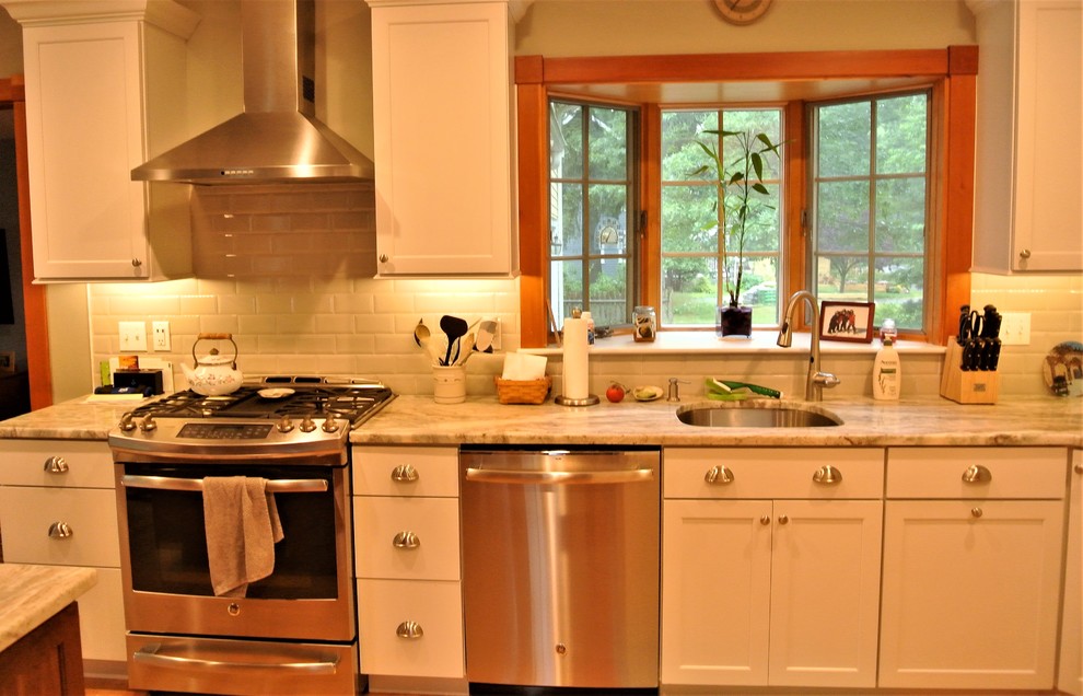 Example of a transitional light wood floor kitchen design in Boston with an undermount sink, shaker cabinets, white cabinets, quartzite countertops, white backsplash, subway tile backsplash, stainless steel appliances and an island