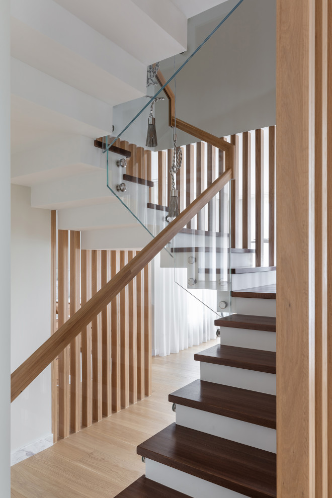 Imagen de escalera en U contemporánea grande con escalones de madera, contrahuellas de hormigón y barandilla de madera