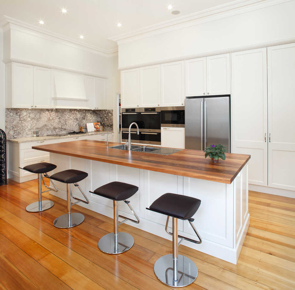 Inspiration for a mid-sized contemporary galley eat-in kitchen in Sydney with a double-bowl sink, shaker cabinets, white cabinets, stainless steel appliances, wood benchtops, multi-coloured splashback, marble splashback, medium hardwood floors and with island.