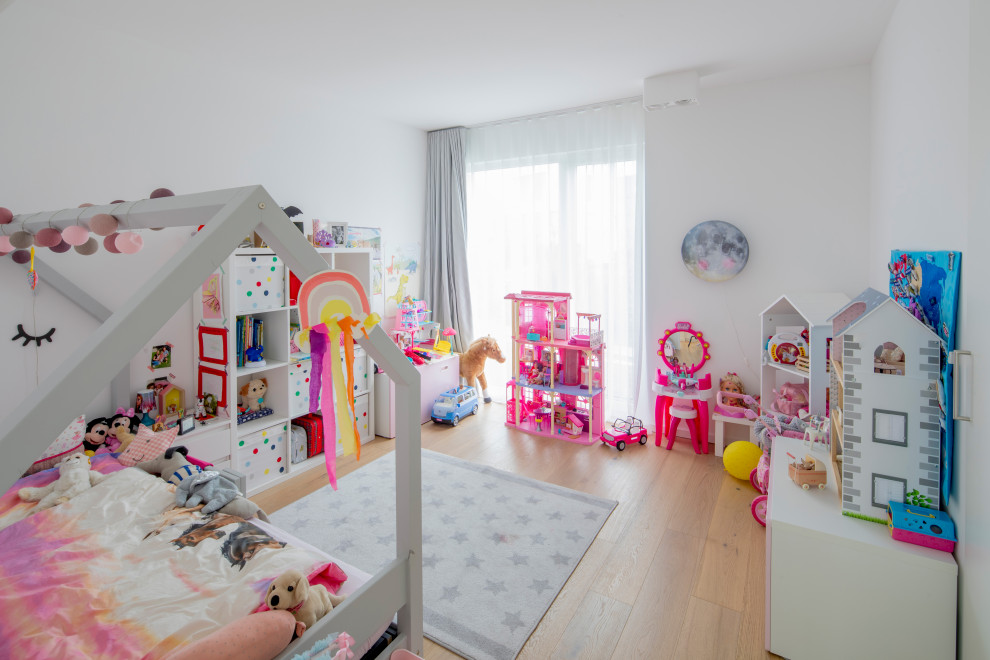 Modelo de dormitorio infantil de 4 a 10 años actual de tamaño medio con paredes blancas, suelo de madera en tonos medios y suelo marrón