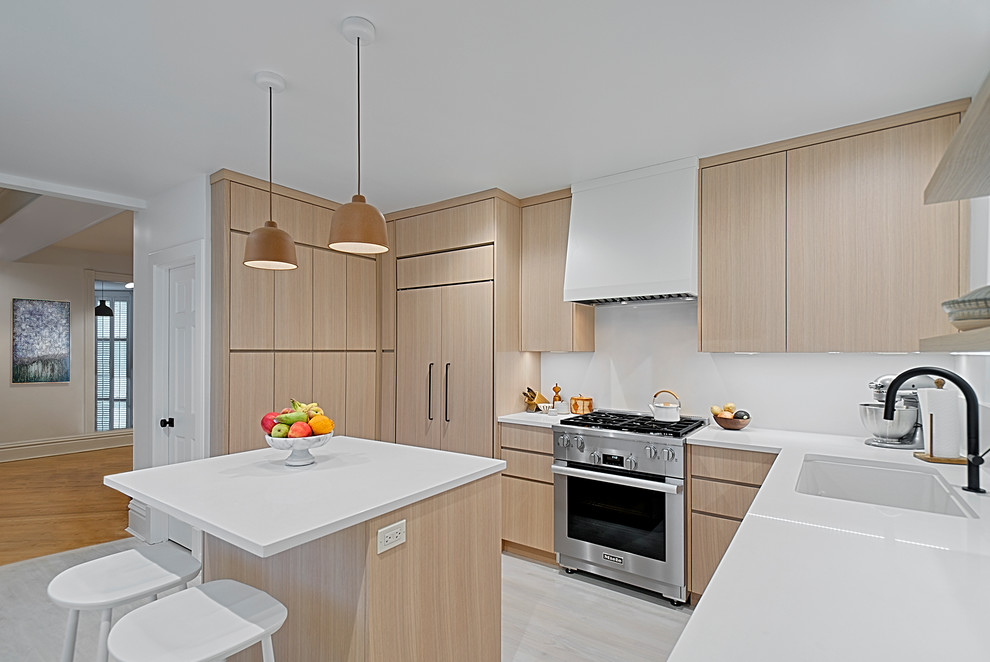 Photo of a small contemporary u-shaped separate kitchen in Chicago with an undermount sink, flat-panel cabinets, light wood cabinets, quartz benchtops, white splashback, stone slab splashback, stainless steel appliances, light hardwood floors, with island, grey floor and white benchtop.