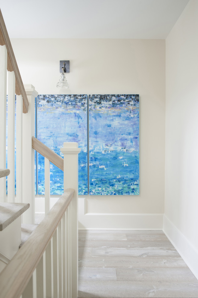 Photo of a mid-sized beach style hallway in Atlanta with white walls, light hardwood floors and beige floor.