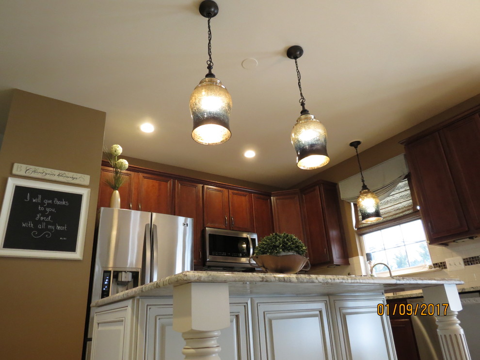 Inspiration for a mid-sized transitional l-shaped ceramic tile eat-in kitchen remodel with an undermount sink, raised-panel cabinets, distressed cabinets, granite countertops, white backsplash, porcelain backsplash, stainless steel appliances and an island
