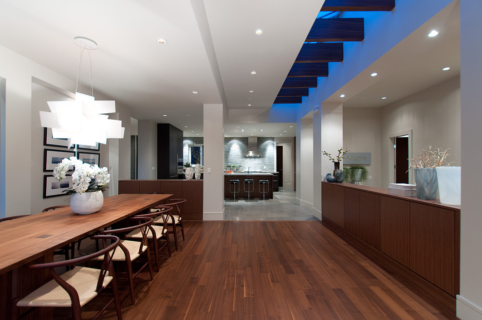 This is an example of a contemporary kitchen/dining combo in Vancouver with white walls and dark hardwood floors.