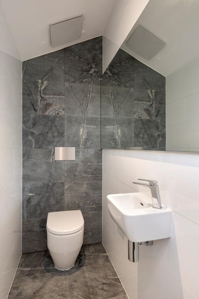 Design ideas for a small contemporary powder room in Melbourne with a wall-mount toilet, stone tile, limestone floors, a wall-mount sink and vaulted.