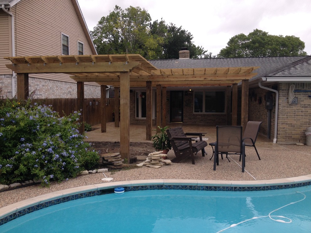 Large traditional backyard patio in Houston with stamped concrete and a pergola.