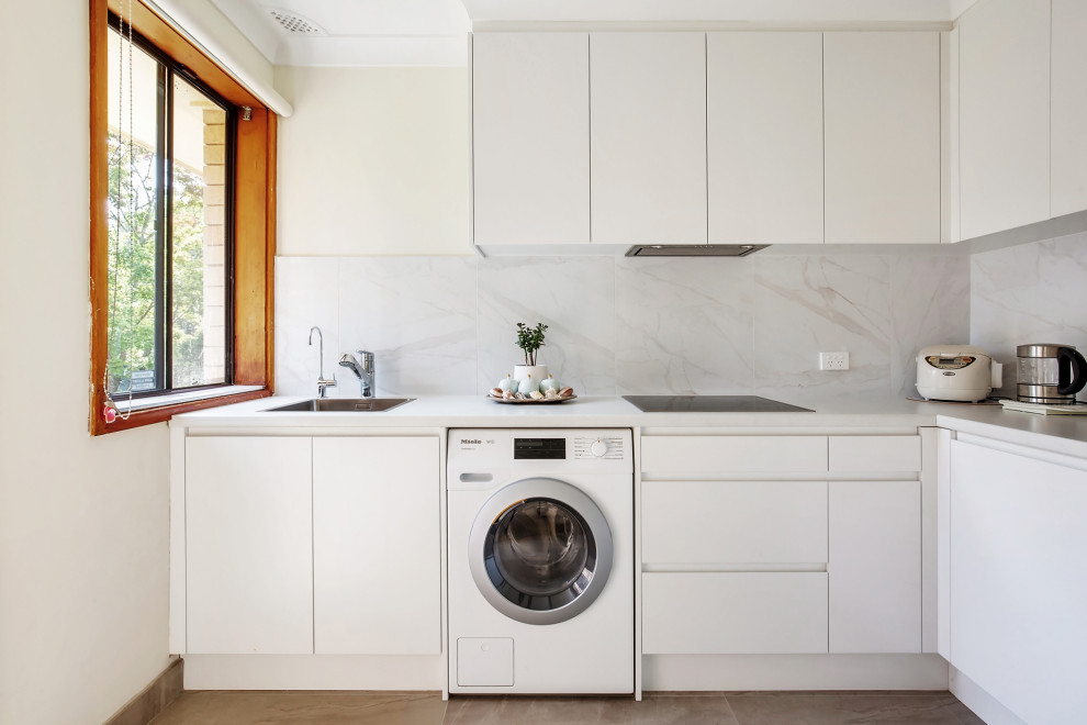 Photo of a contemporary l-shaped kitchen in Newcastle - Maitland with a drop-in sink, flat-panel cabinets, white cabinets, white splashback, no island, brown floor and white benchtop.