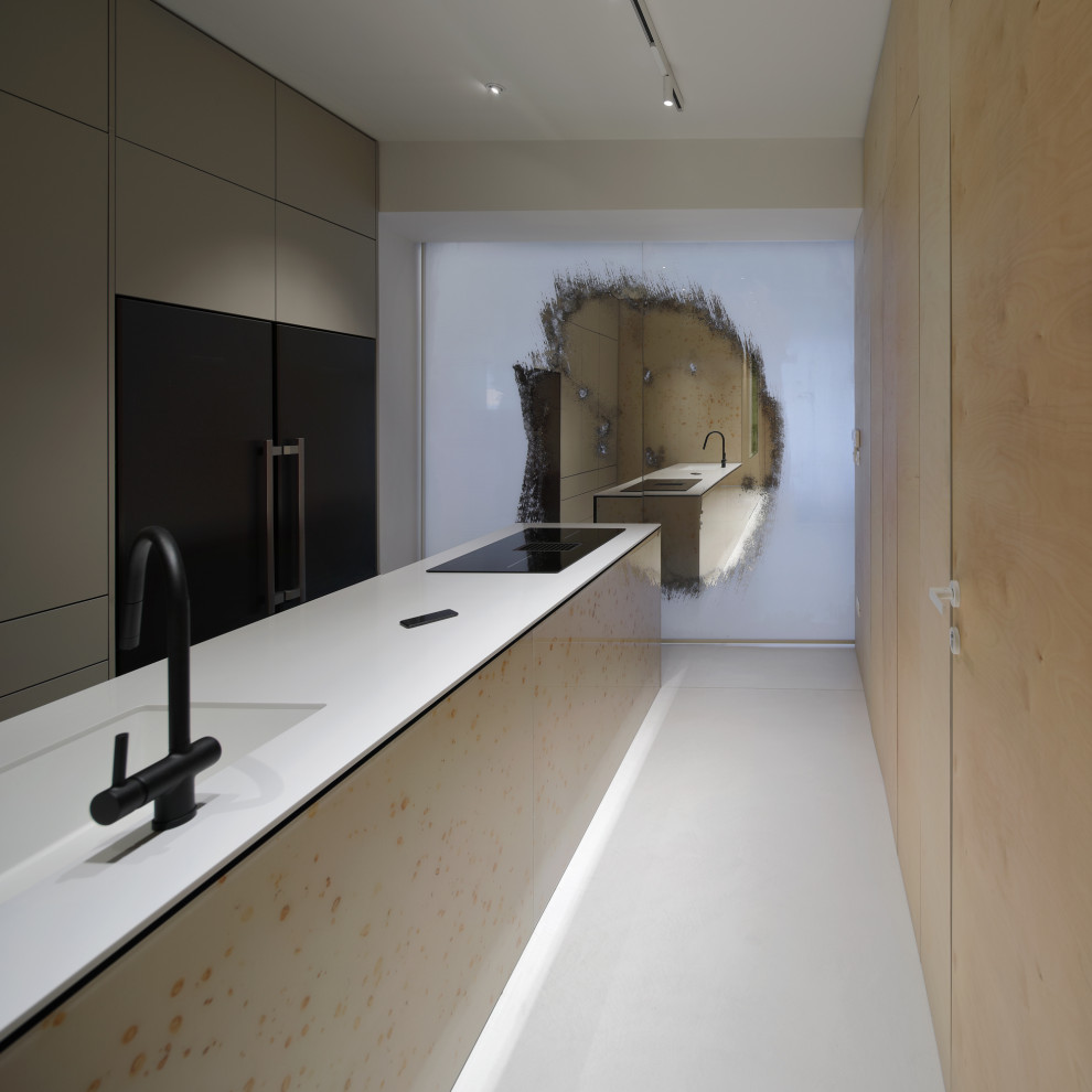 Immagine di una grande cucina minimalista con lavello da incasso, ante a filo, ante grigie, elettrodomestici neri, pavimento in cemento, pavimento grigio e top bianco