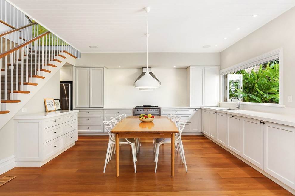 Inspiration for a large transitional u-shaped eat-in kitchen in Sydney with a double-bowl sink, recessed-panel cabinets, white cabinets, terrazzo benchtops, white splashback, glass sheet splashback, stainless steel appliances, medium hardwood floors, no island and brown floor.