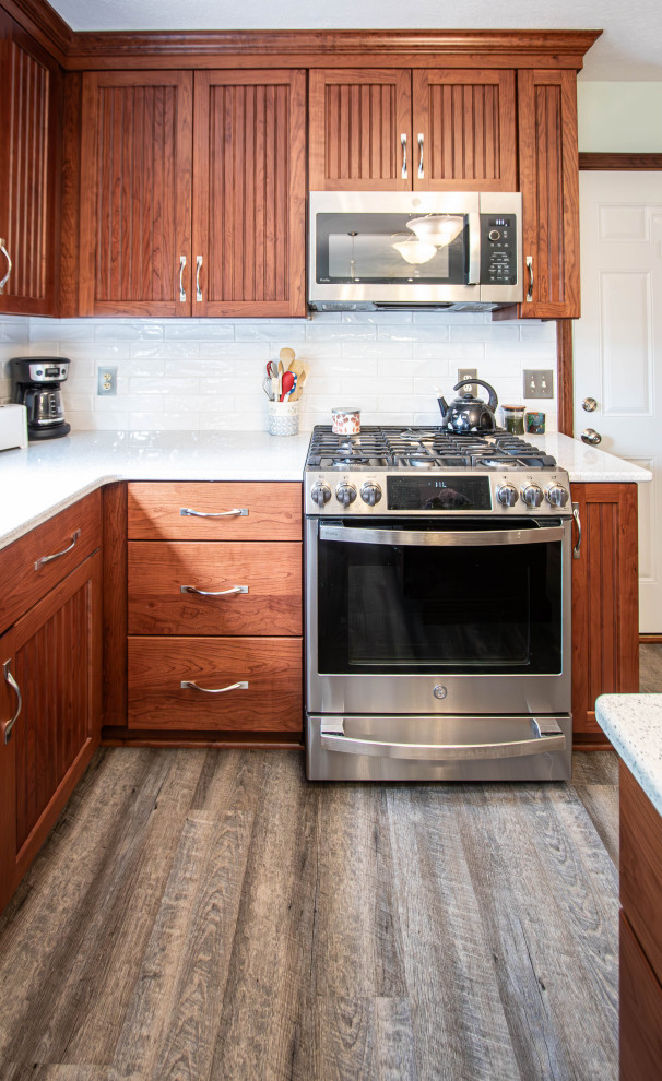 Idéer för att renovera ett mellanstort vintage beige beige kök, med en undermonterad diskho, luckor med profilerade fronter, skåp i mellenmörkt trä, bänkskiva i kvarts, vitt stänkskydd, stänkskydd i tunnelbanekakel, rostfria vitvaror, vinylgolv, en köksö och grått golv