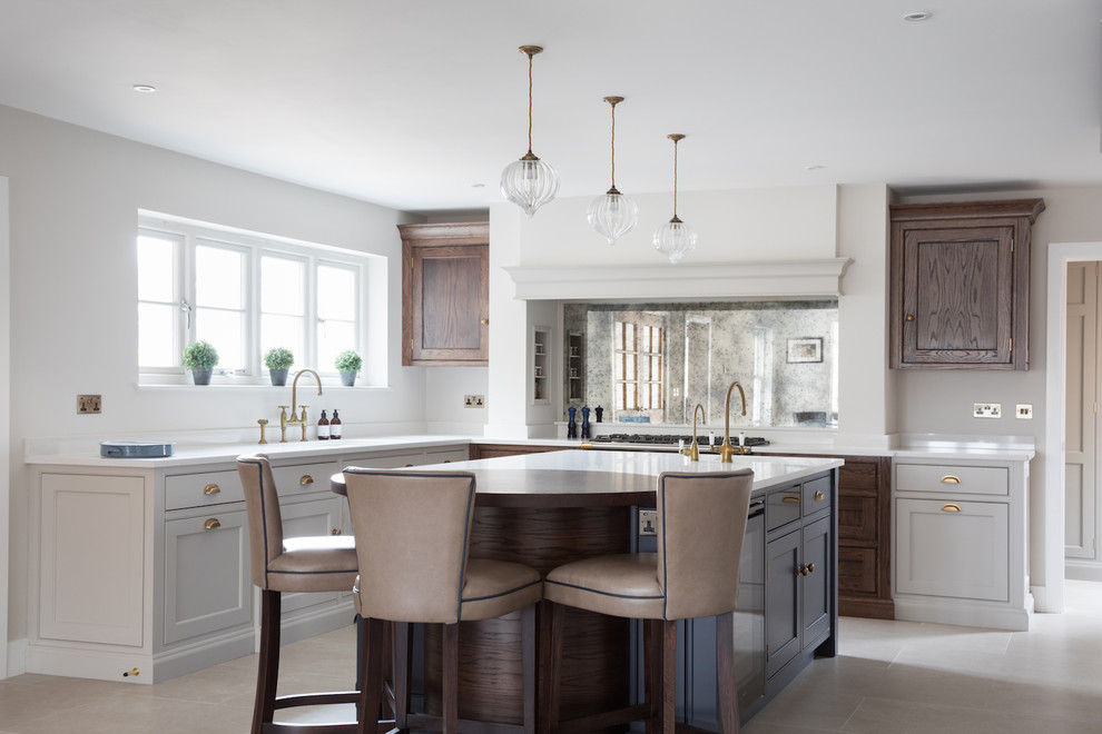 This is an example of a large transitional l-shaped kitchen in Essex with shaker cabinets, dark wood cabinets, mirror splashback and beige floor.
