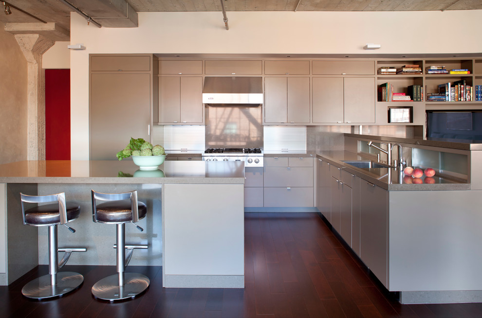 Photo of a small industrial l-shaped eat-in kitchen in San Francisco with an undermount sink, flat-panel cabinets, grey cabinets, metallic splashback, dark hardwood floors, with island, stainless steel appliances, quartz benchtops and stone tile splashback.