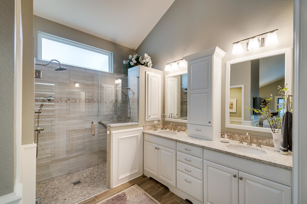 Mid-sized transitional master beige tile and porcelain tile porcelain tile and brown floor walk-in shower photo in Denver with beige walls, an undermount sink, raised-panel cabinets, beige cabinets, quartzite countertops and a hinged shower door