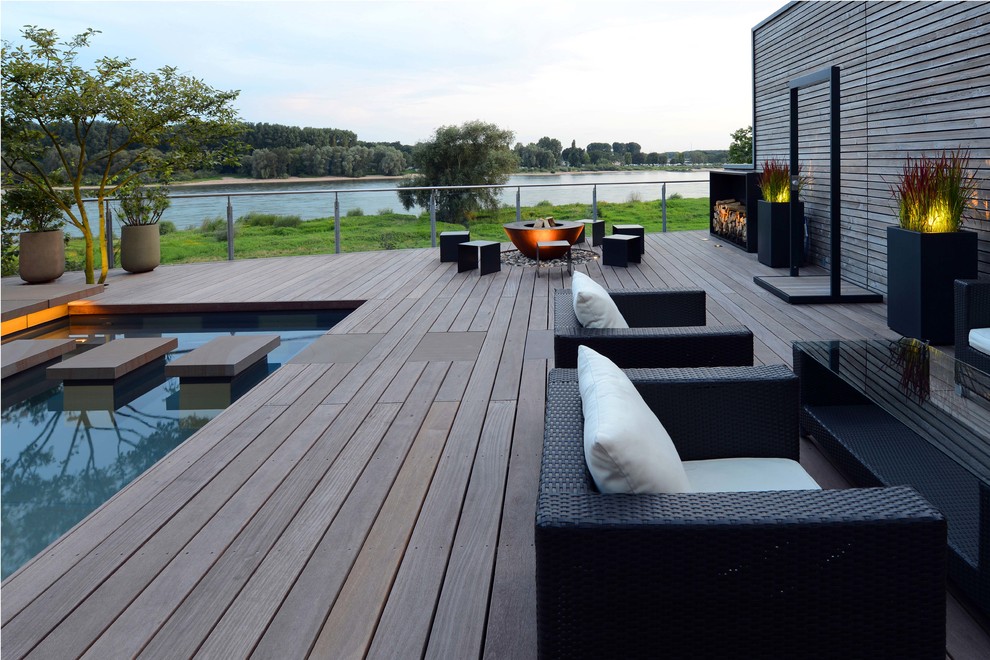 Small contemporary side yard deck in Cologne with a fire feature.