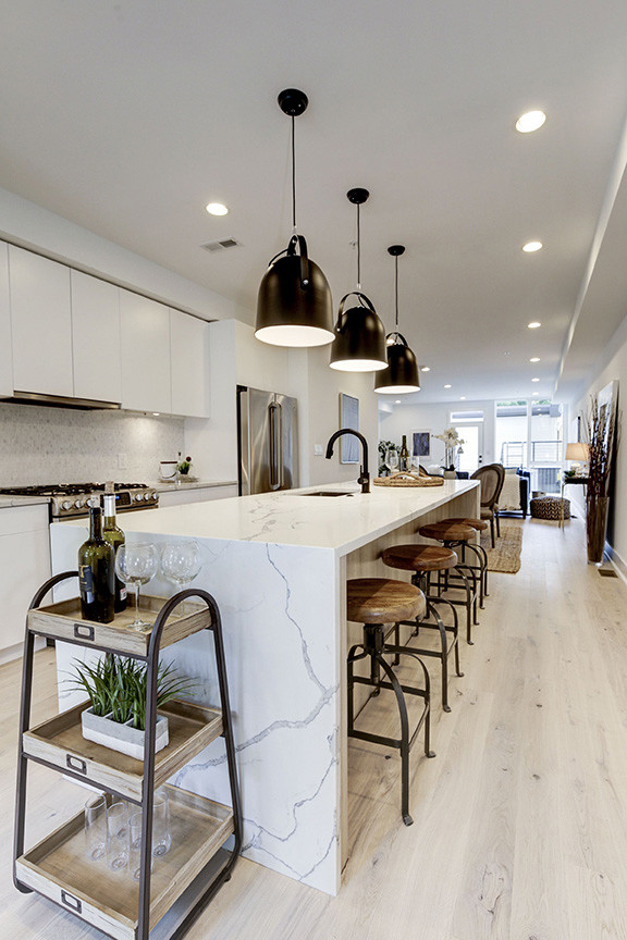 Inspiration for a contemporary galley kitchen with flat-panel cabinets, white cabinets, solid surface benchtops, stainless steel appliances and with island.