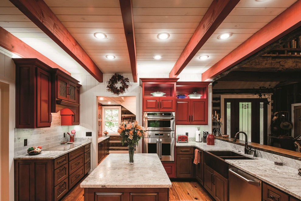 Inspiration for a large rustic l-shaped brown floor kitchen remodel with a farmhouse sink, raised-panel cabinets, brown cabinets, stainless steel appliances and an island