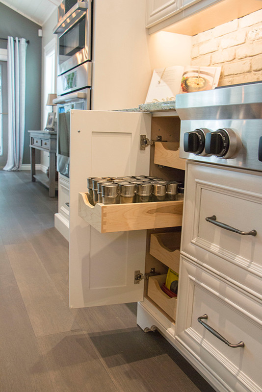 Home design - large transitional l-shaped home design idea with a double-bowl sink, shaker cabinets, white cabinets, beige backsplash, stainless steel appliances and an island