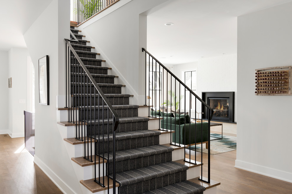 Country carpeted straight staircase in Minneapolis with carpet risers and metal railing.