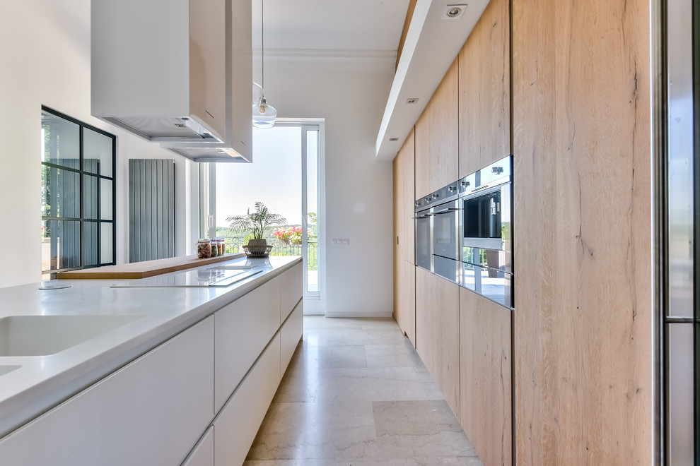 Inspiration for a large contemporary galley eat-in kitchen in Paris with an integrated sink, light wood cabinets, solid surface benchtops, panelled appliances, with island, beige floor and white benchtop.