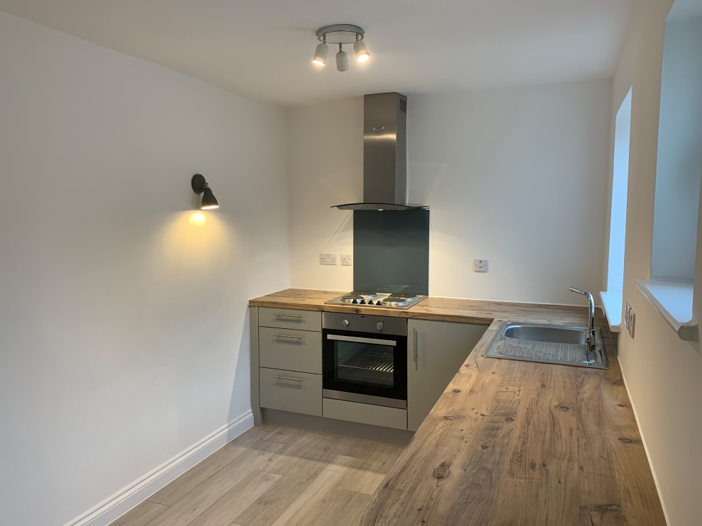 Design ideas for a small modern galley enclosed kitchen in Buckinghamshire with a single-bowl sink, flat-panel cabinets, turquoise cabinets, wood worktops, green splashback, metal splashback, white appliances, laminate floors, no island, multi-coloured floors and multicoloured worktops.
