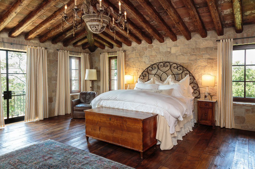 Inspiration for a mediterranean guest bedroom in Orange County with beige walls, dark hardwood floors and brown floor.