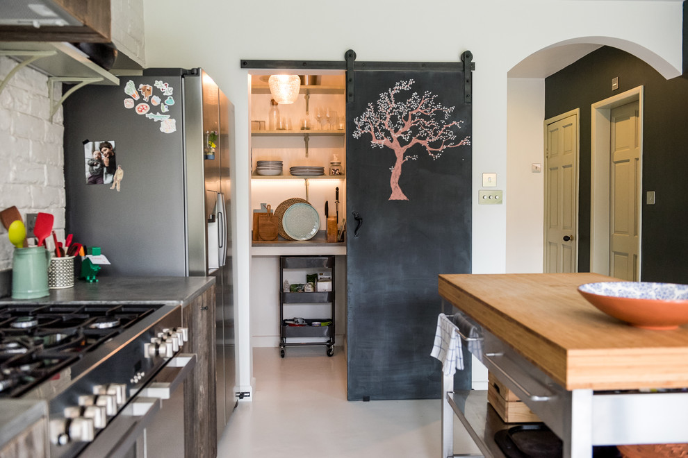 Inspiration for a mid-sized eclectic single-wall open plan kitchen in London with a single-bowl sink, flat-panel cabinets, medium wood cabinets, concrete benchtops, white splashback, brick splashback, stainless steel appliances, with island, white floor and grey benchtop.