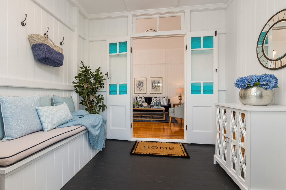 This is an example of a beach style vestibule in Brisbane with white walls, painted wood floors and black floor.