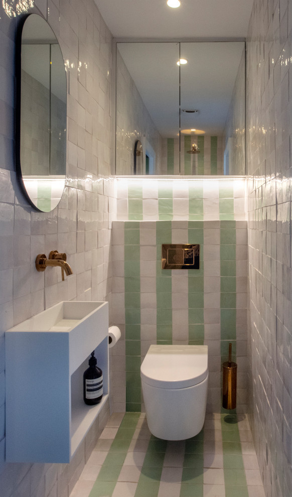 Small contemporary master wet room bathroom in London with flat-panel cabinets, white cabinets, a wall-mount toilet, white tile, ceramic tile, white walls, cement tiles, a wall-mount sink, green floor, an enclosed toilet, a single vanity and a floating vanity.