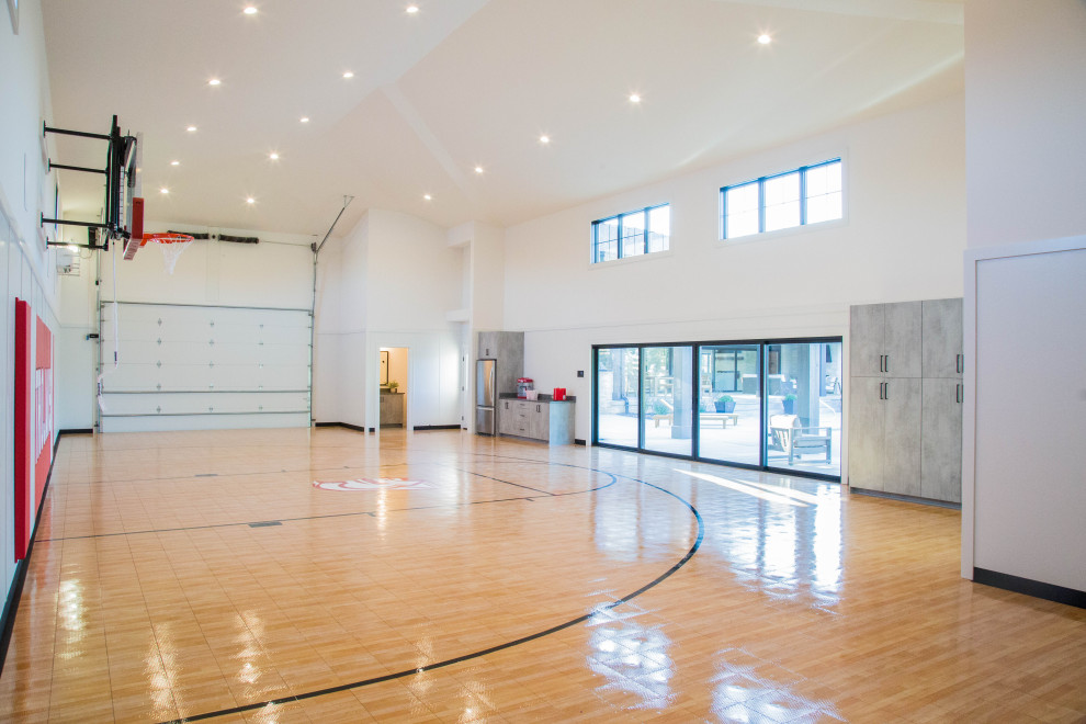 Cette photo montre un très grand terrain de sport intérieur moderne avec un mur beige et un sol marron.