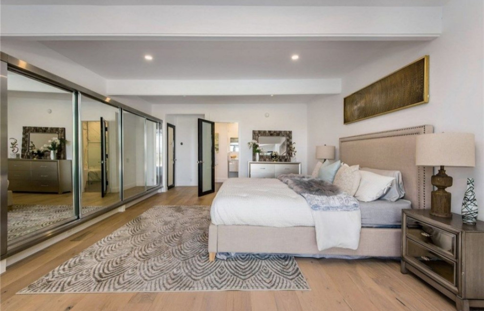 This is an example of a large modern master bedroom in Los Angeles with white walls, light hardwood floors and brown floor.