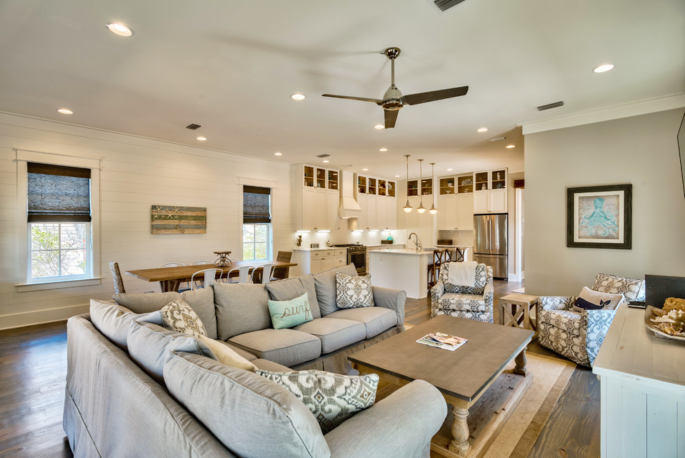 Photo of a beach style open concept living room in Miami with white walls, medium hardwood floors, no fireplace and a wall-mounted tv.