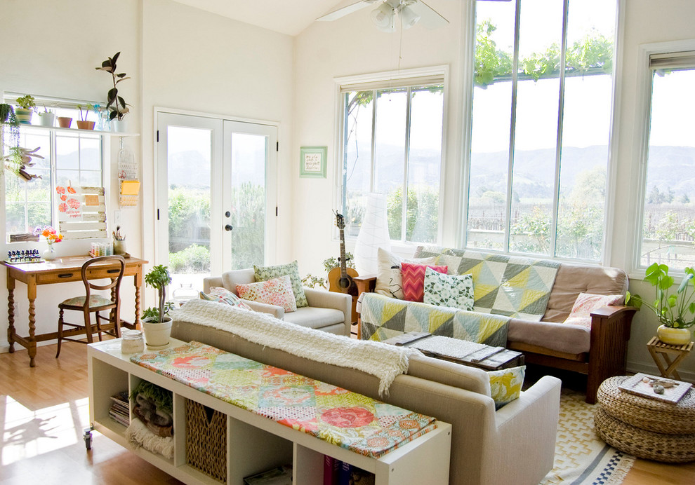 This is an example of a country living room in Santa Barbara with a music area, white walls and medium hardwood floors.