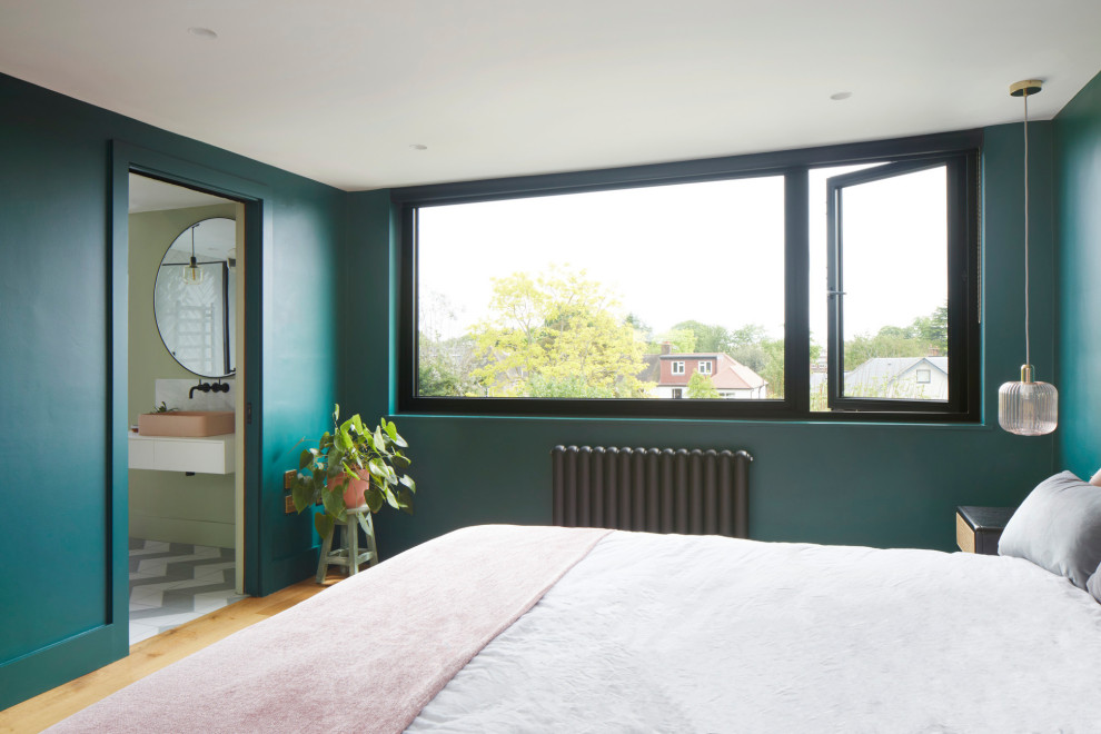 Inspiration pour une grande chambre parentale design avec un mur vert et un sol en bois brun.