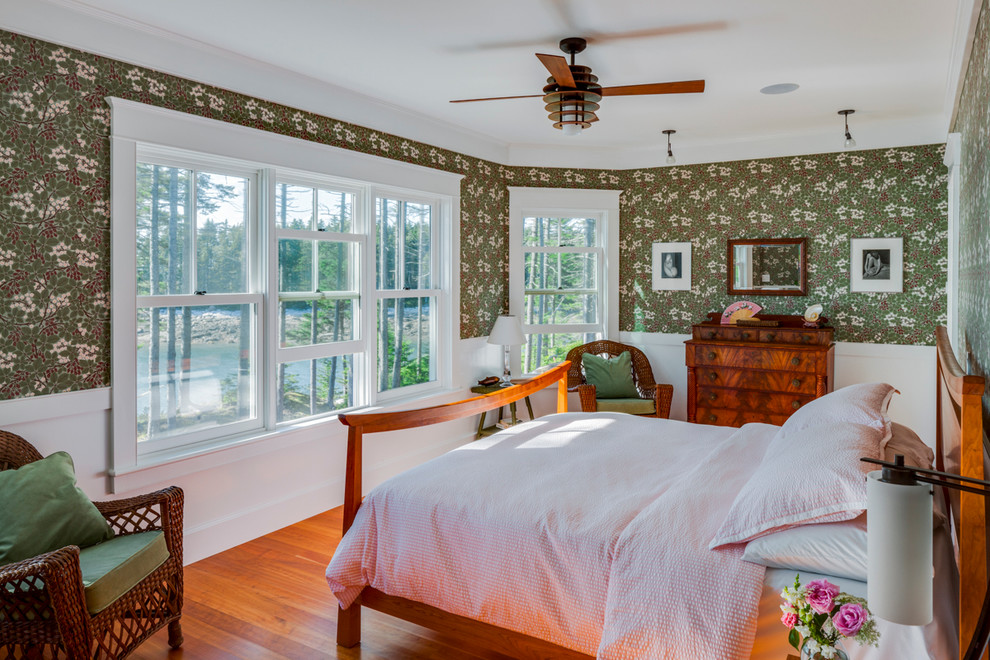 This is an example of a mid-sized traditional master bedroom in Portland Maine with green walls, dark hardwood floors, no fireplace and orange floor.