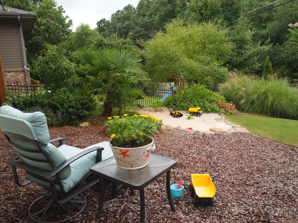 Photo of a mid-sized tropical backyard full sun garden for spring in Atlanta with with outdoor playset.