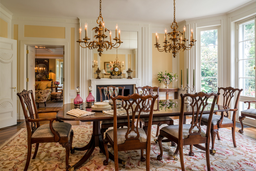 Photo of a traditional separate dining room in Philadelphia with yellow walls, dark hardwood floors and a standard fireplace.