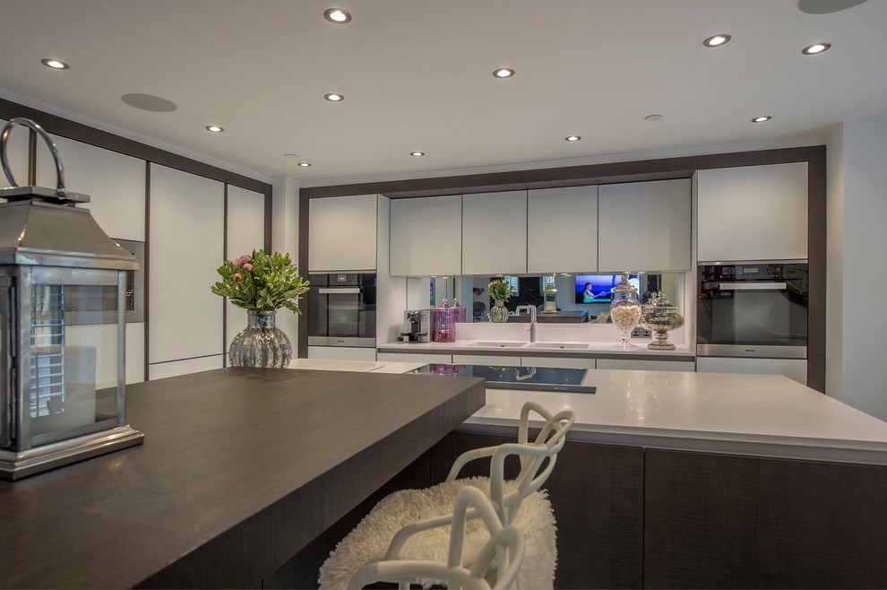 Design ideas for a large modern l-shaped eat-in kitchen in Other with a double-bowl sink, flat-panel cabinets, white cabinets, solid surface benchtops, metallic splashback, mirror splashback, stainless steel appliances, porcelain floors, with island and white floor.